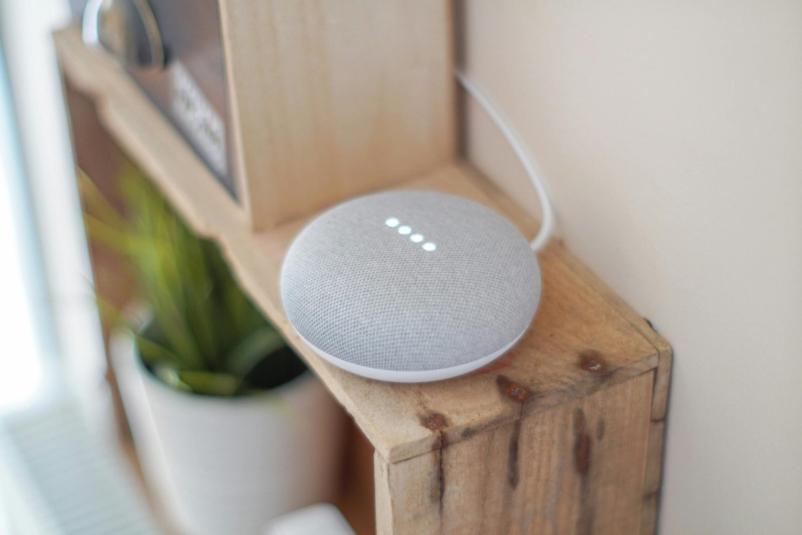 A smart grey speaker on a wooden cupboard.